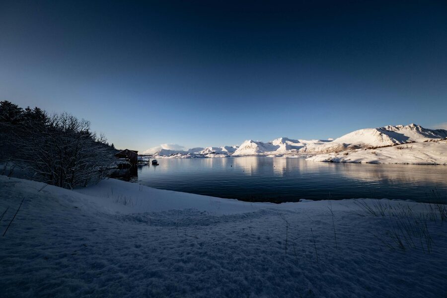 Snow-covered mountains and lake at dusk near Tromsø