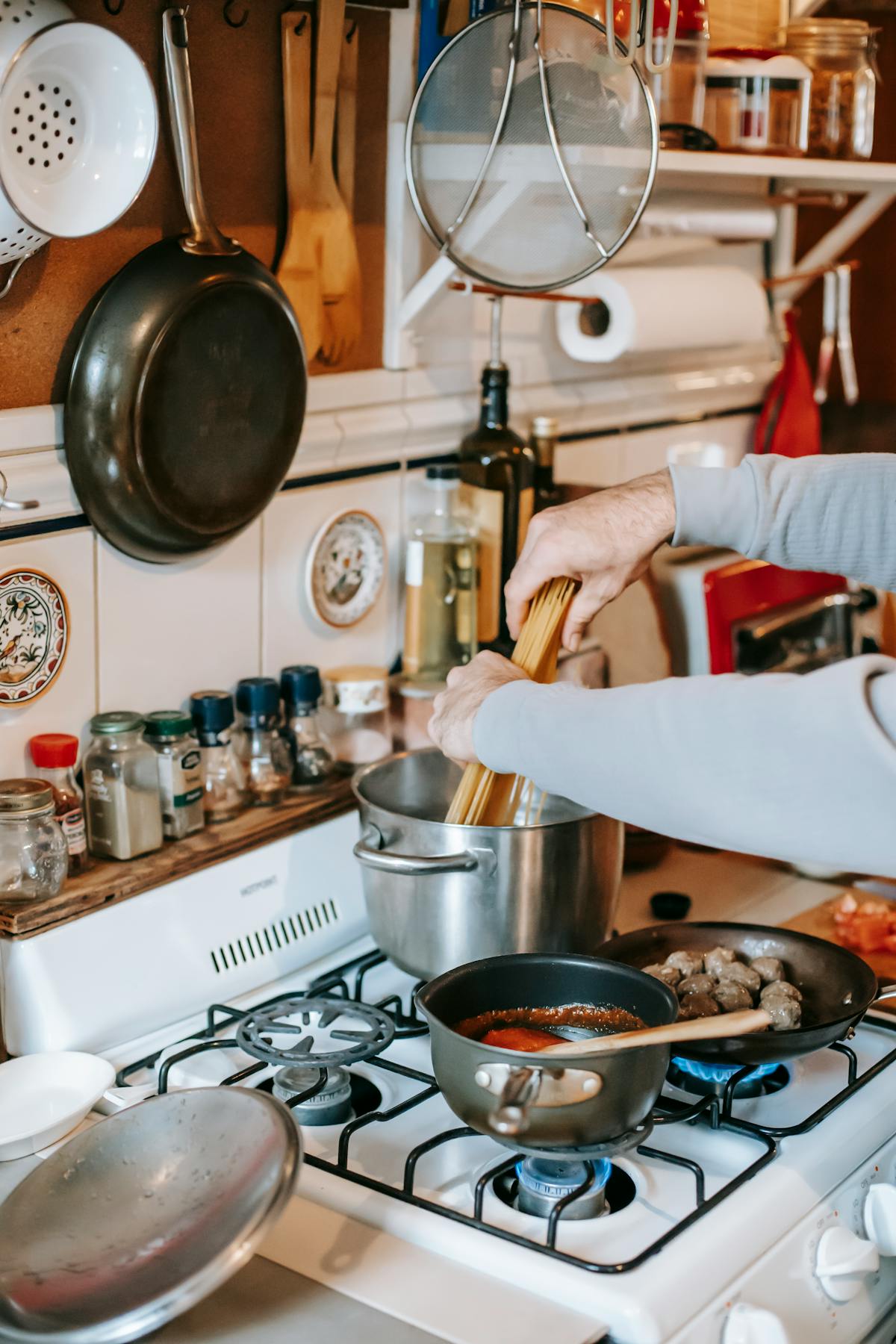 Person putting fresh pasta into a large saucepan of boiling water on a gas stove