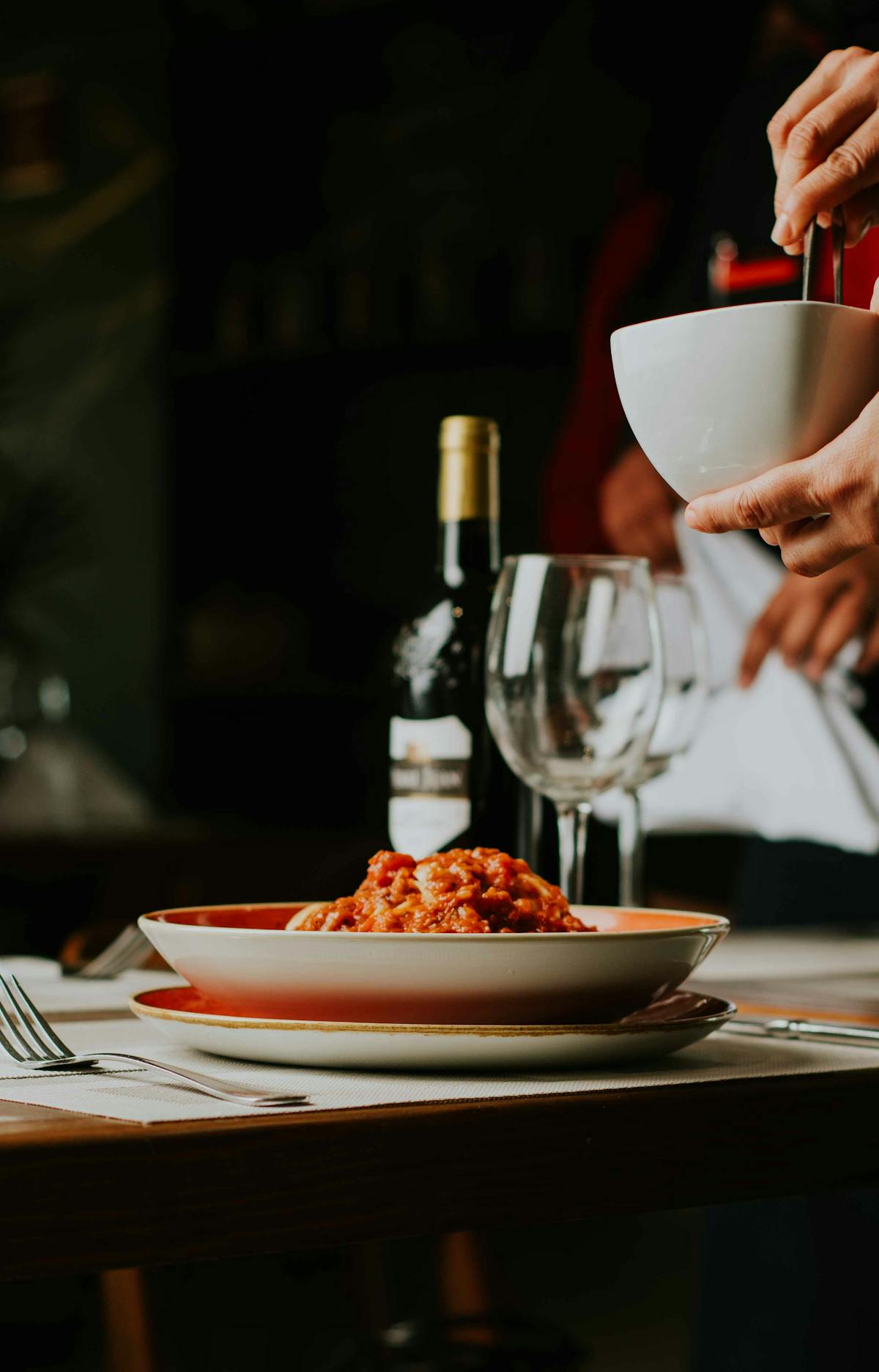 Plate of spaghetti with a glass of red wine on a restaurant table