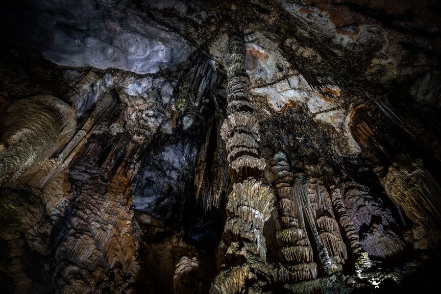 Dramatic stalactite and stalagmite formations illuminated inside a large Spanish cave
