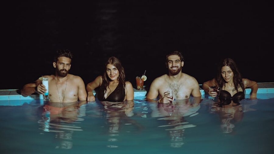 Group with drinks in pool at night
