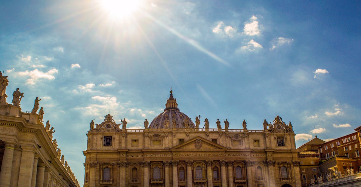 Wide view of St. Peters Basilica under a bright blue sky with the dome rising above