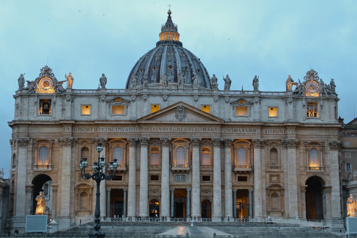 The illuminated facade of St. Peters Basilica at dusk with warm golden lighting