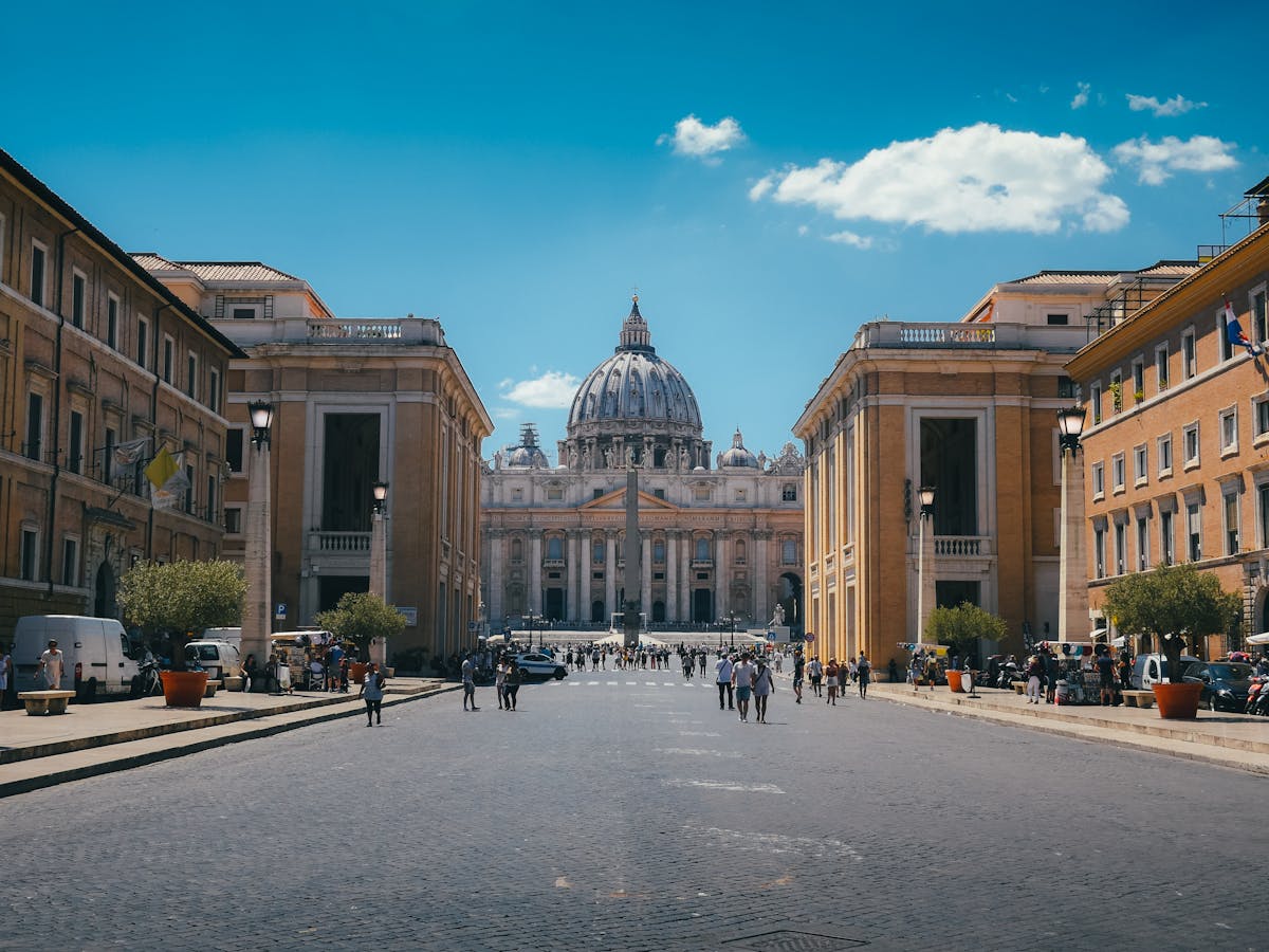 Tourists and visitors walking toward St. Peters Basilica entrance on a sunny day