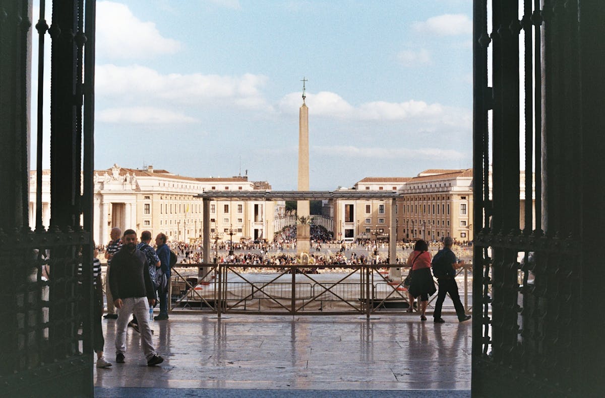 The Egyptian obelisk in St. Peters Square with visitors walking around the piazza