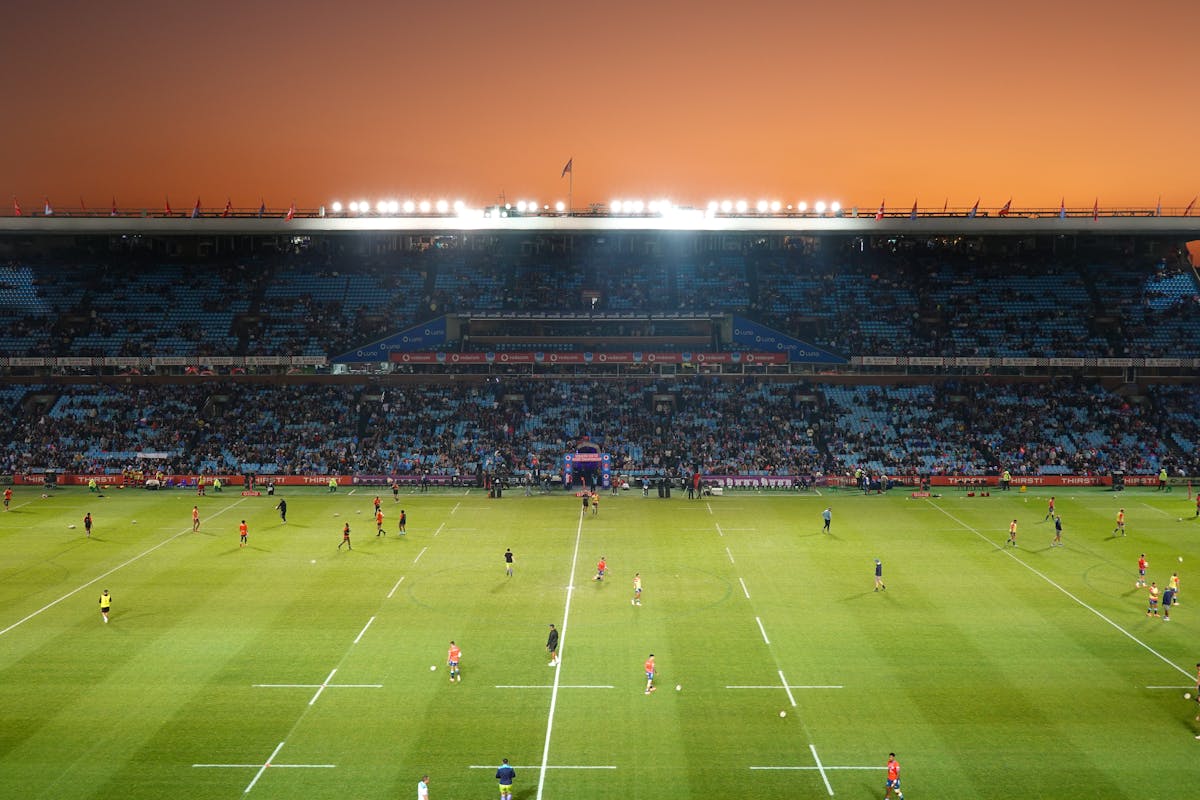 Rugby match at sunset in large stadium with waving flags