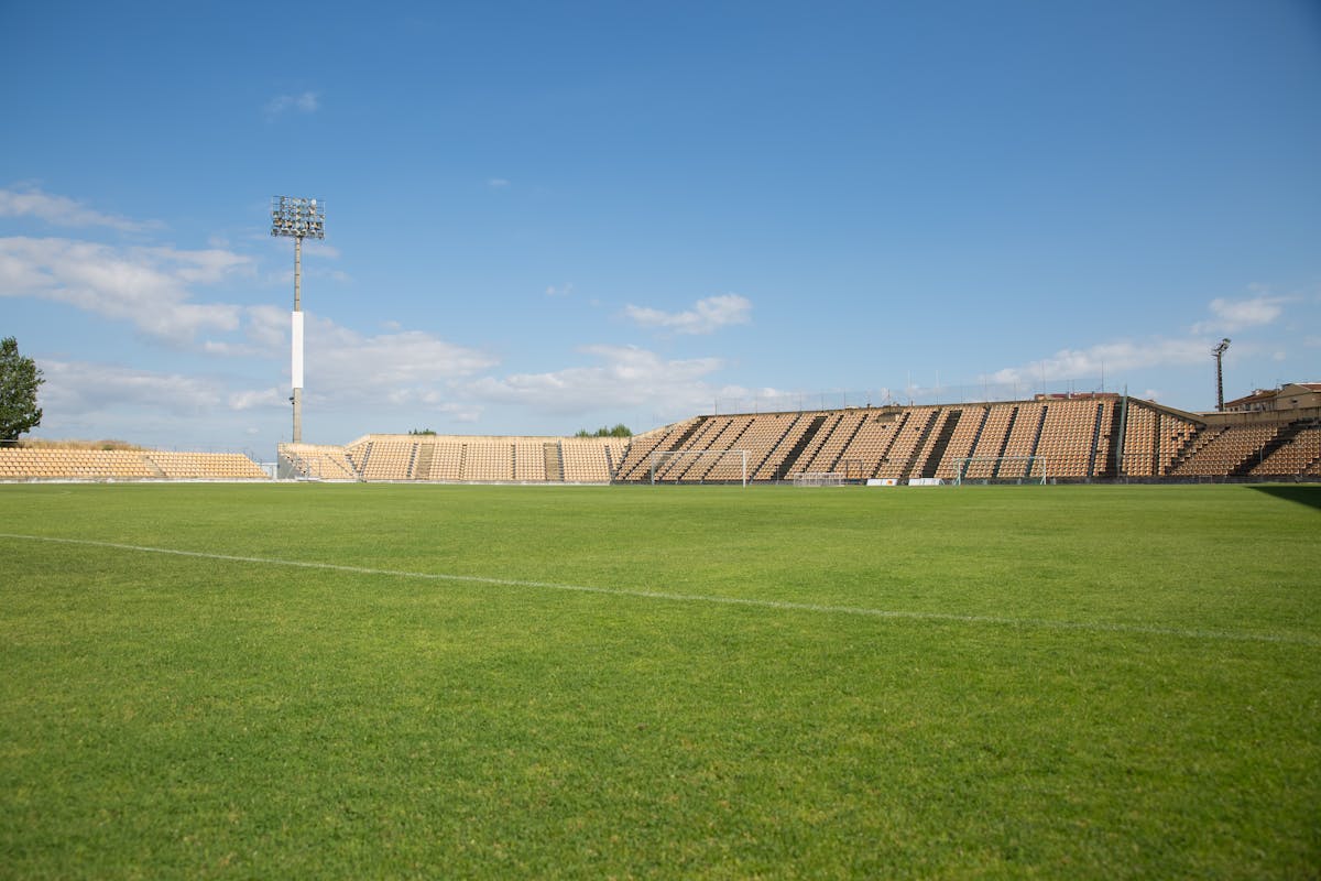 Empty football stadium with seats under clear blue sky