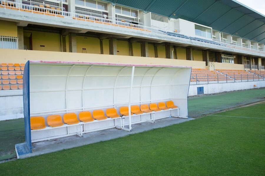 Players bench beside the pitch at an empty football stadium