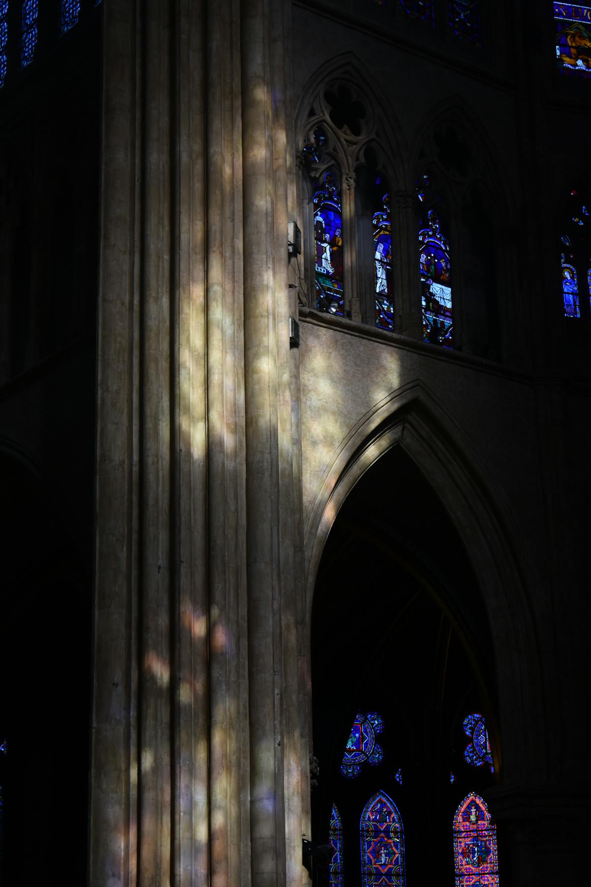Sunlight filtering through colorful stained glass windows inside a Gothic cathedral casting rainbow reflections