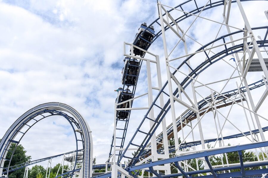 Steel roller coaster track at an amusement park under blue skies