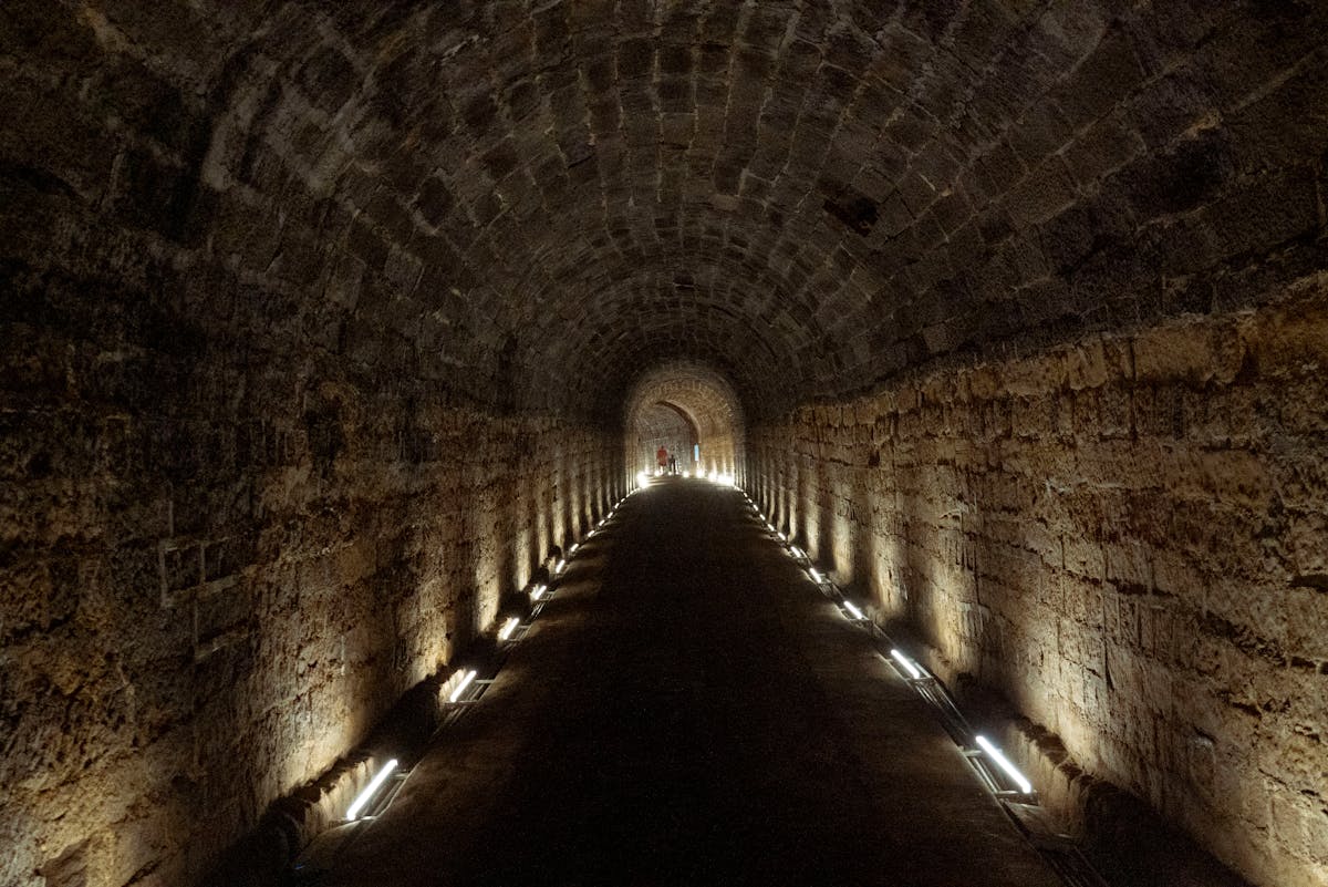 Illuminated narrow stone tunnel passage extending into the distance
