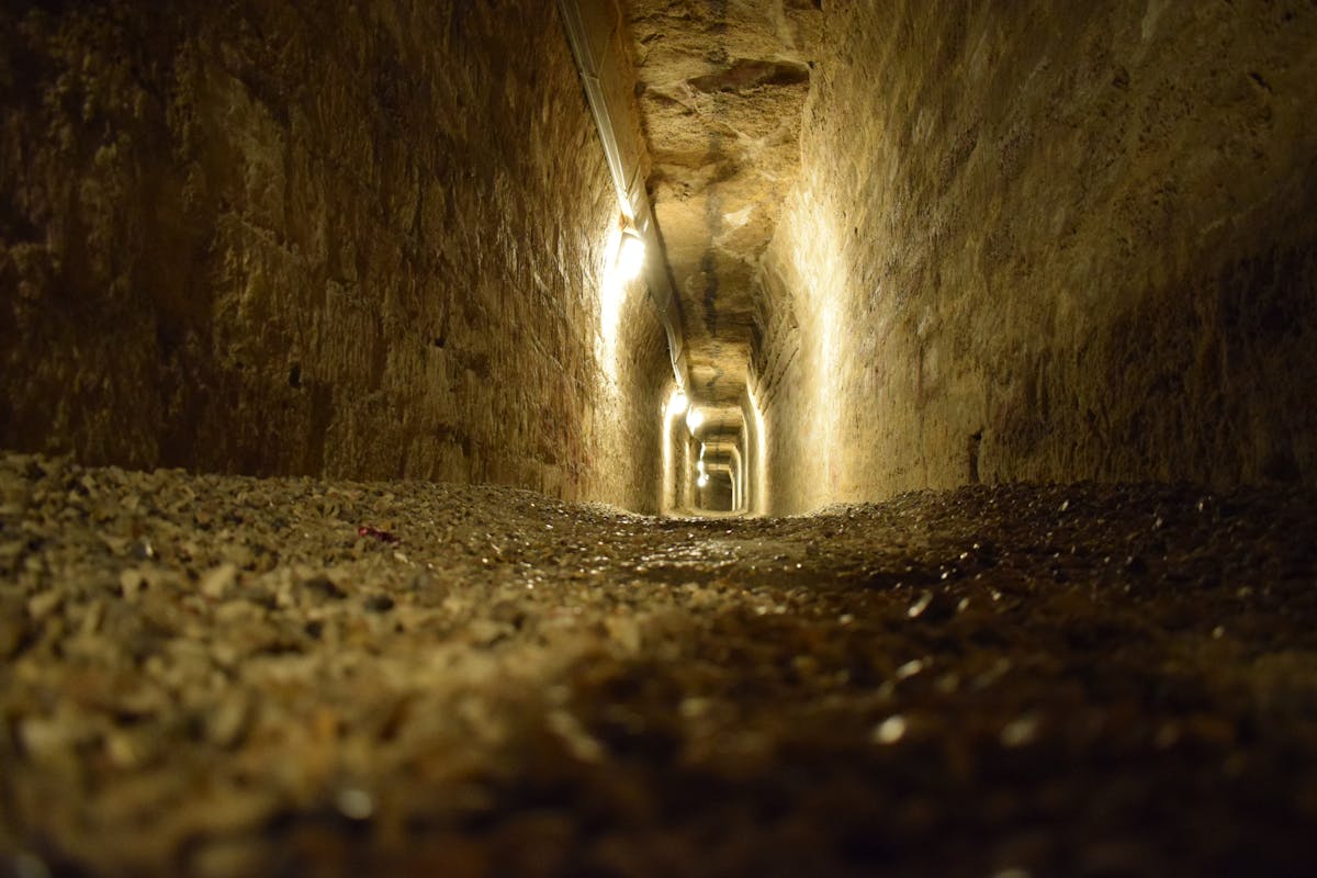 A dimly lit stone tunnel stretching into the darkness beneath Paris