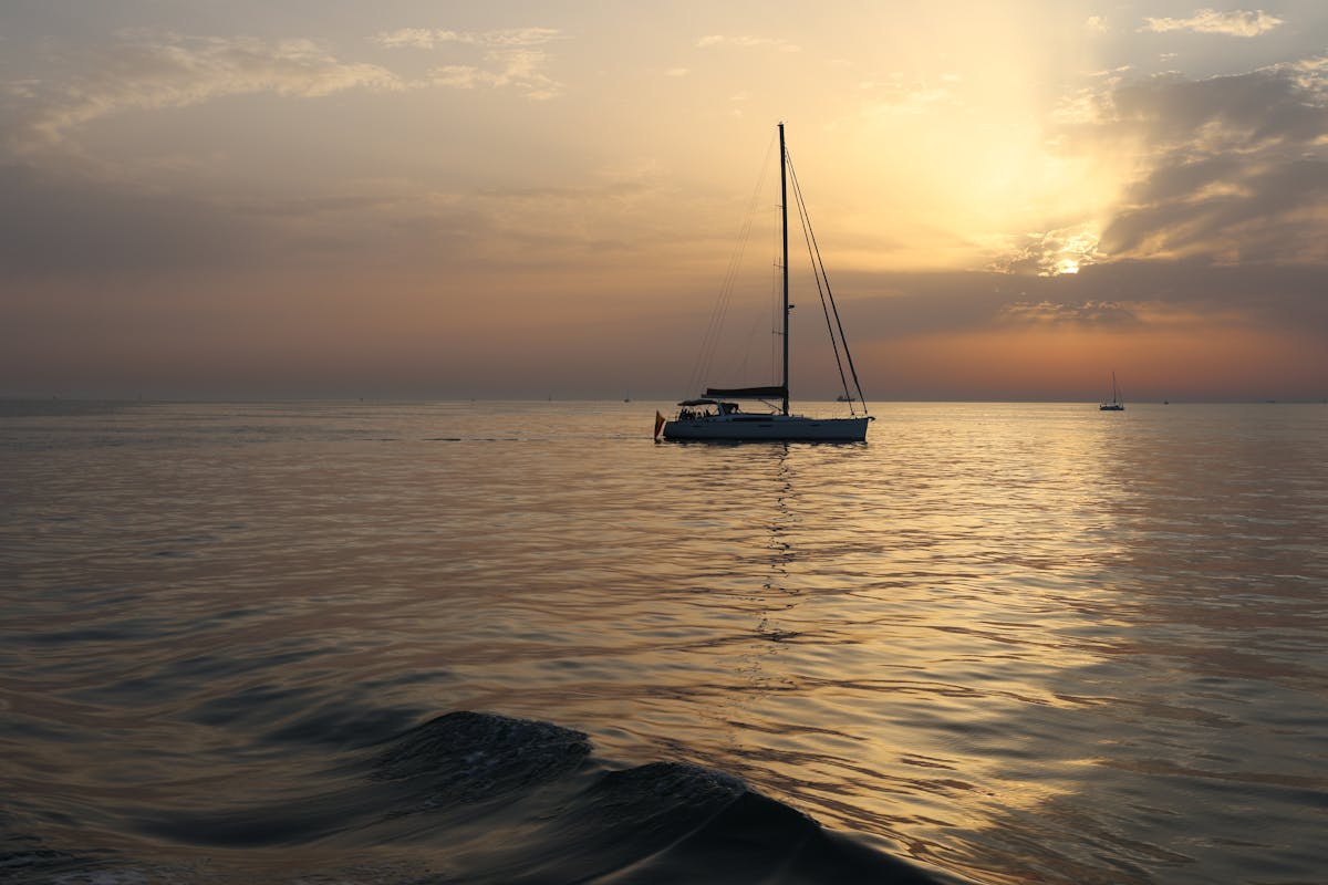 Silhouette of a sailboat on the shimmering sea during golden sunset over the Mediterranean