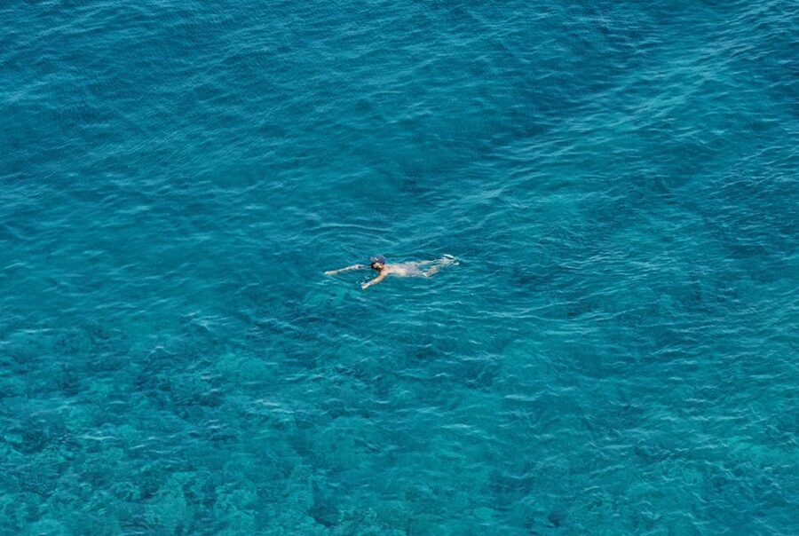 Swimmer in turquoise Greek waters aerial