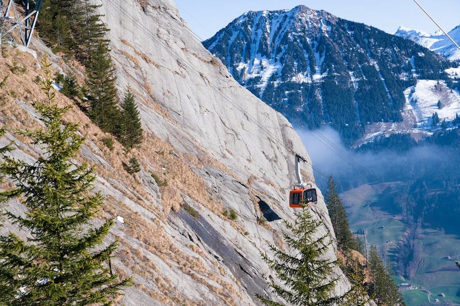 Red cable car ascending Swiss Alps rocky mountain