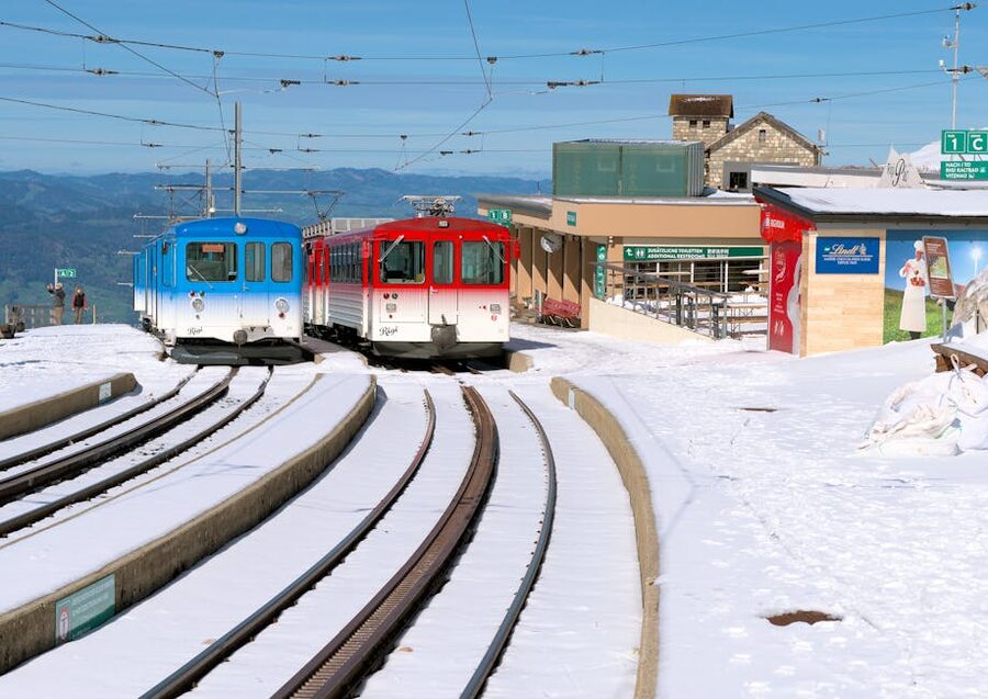 Red and blue trains at snowy Swiss station