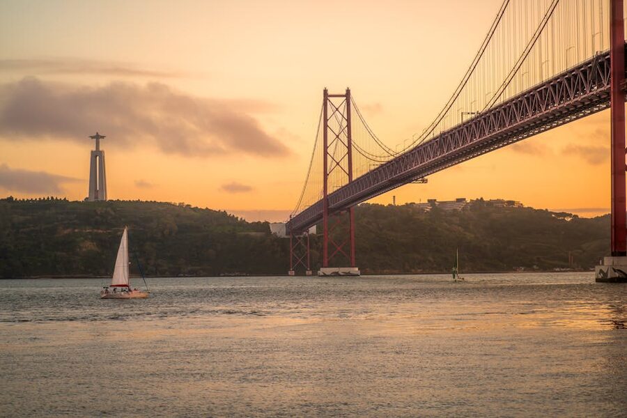 Sunset sailboat near 25 de Abril Bridge Tagus Lisbon