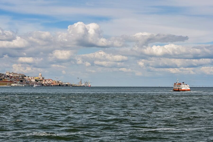 Ferry on Tagus River with Lisbon skyline and clouds