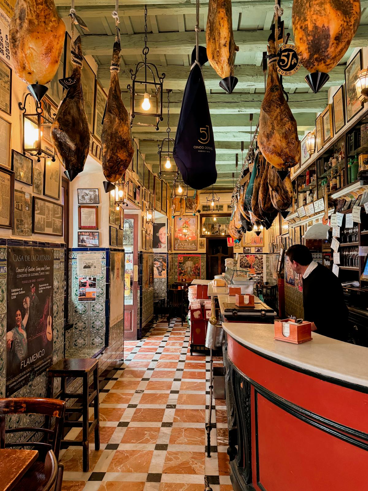 Traditional tapas bar in Seville Spain with hams hanging from the ceiling and colorful tiles