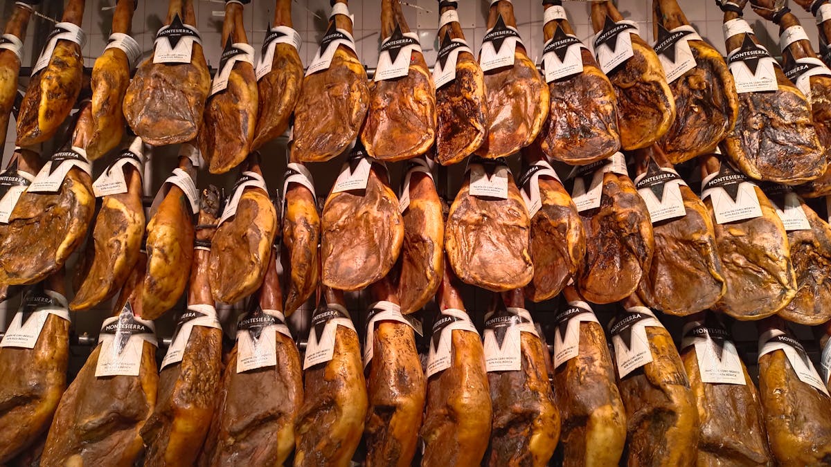 Rows of jamon iberico ham legs hanging on display in a Spanish market