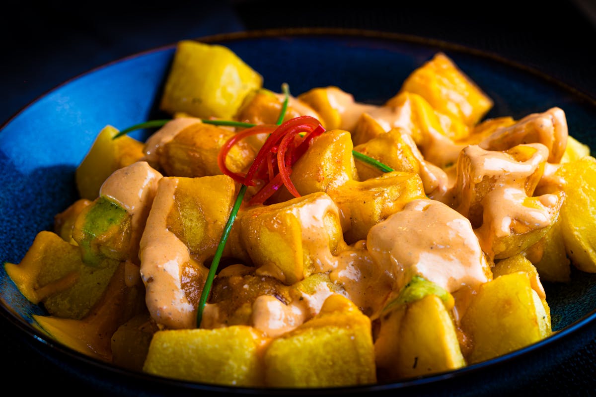 A plate of patatas bravas topped with spicy bravas sauce