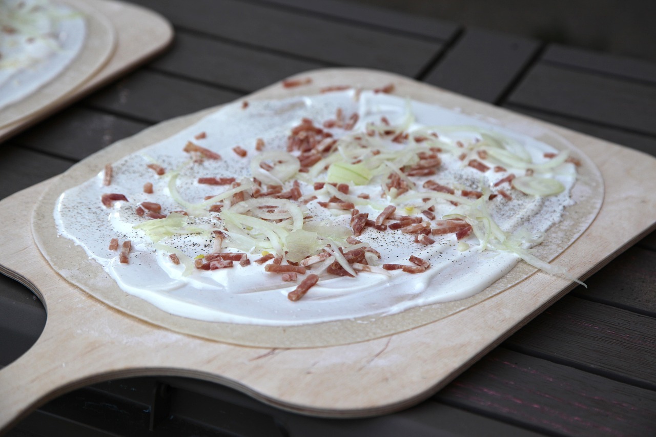Traditional Alsatian tarte flambee with bacon and onion on wooden board