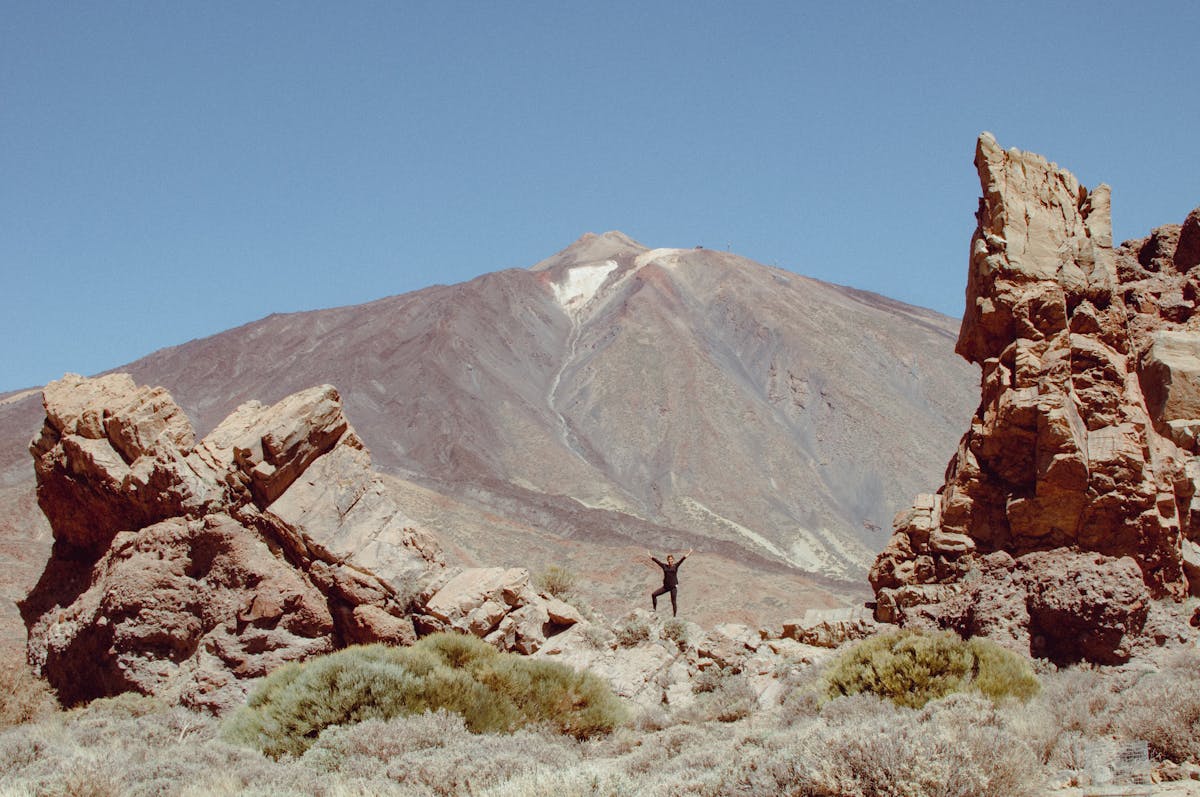 A person standing among dark volcanic rocks at the summit area of Mount Teide Tenerife
