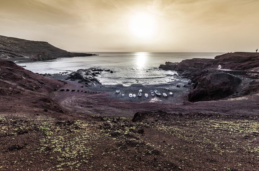 Lago Verde green lagoon surrounded by dark volcanic rock in Lanzarote
