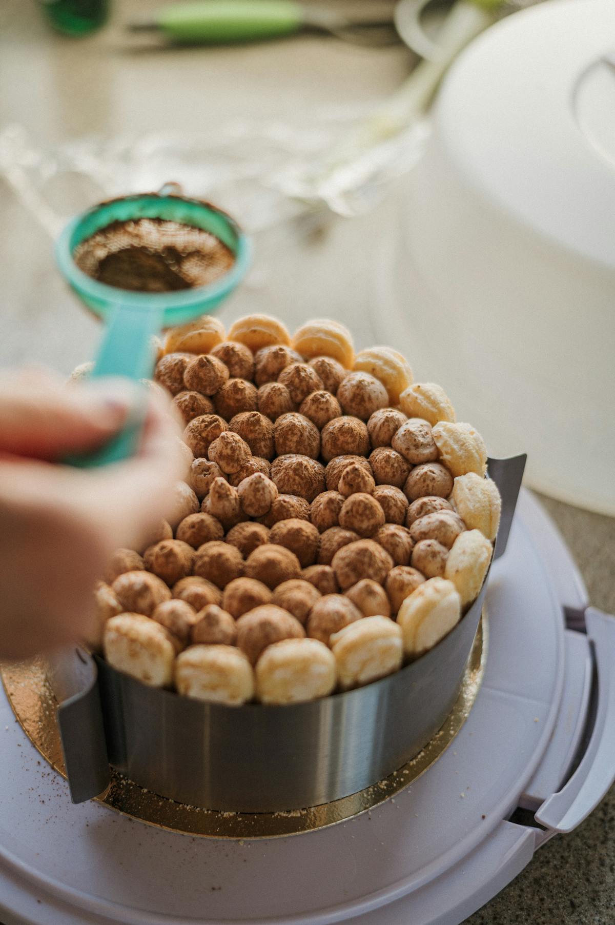 Close-up of cocoa powder being sifted over a homemade tiramisu cake