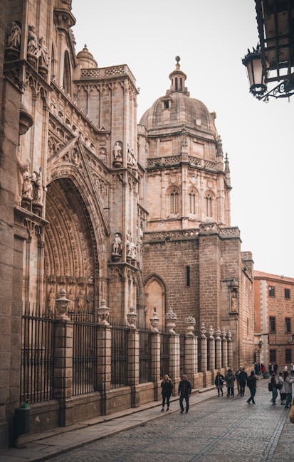 Sun-dappled narrow street in Toledo with medieval stone buildings on both sides