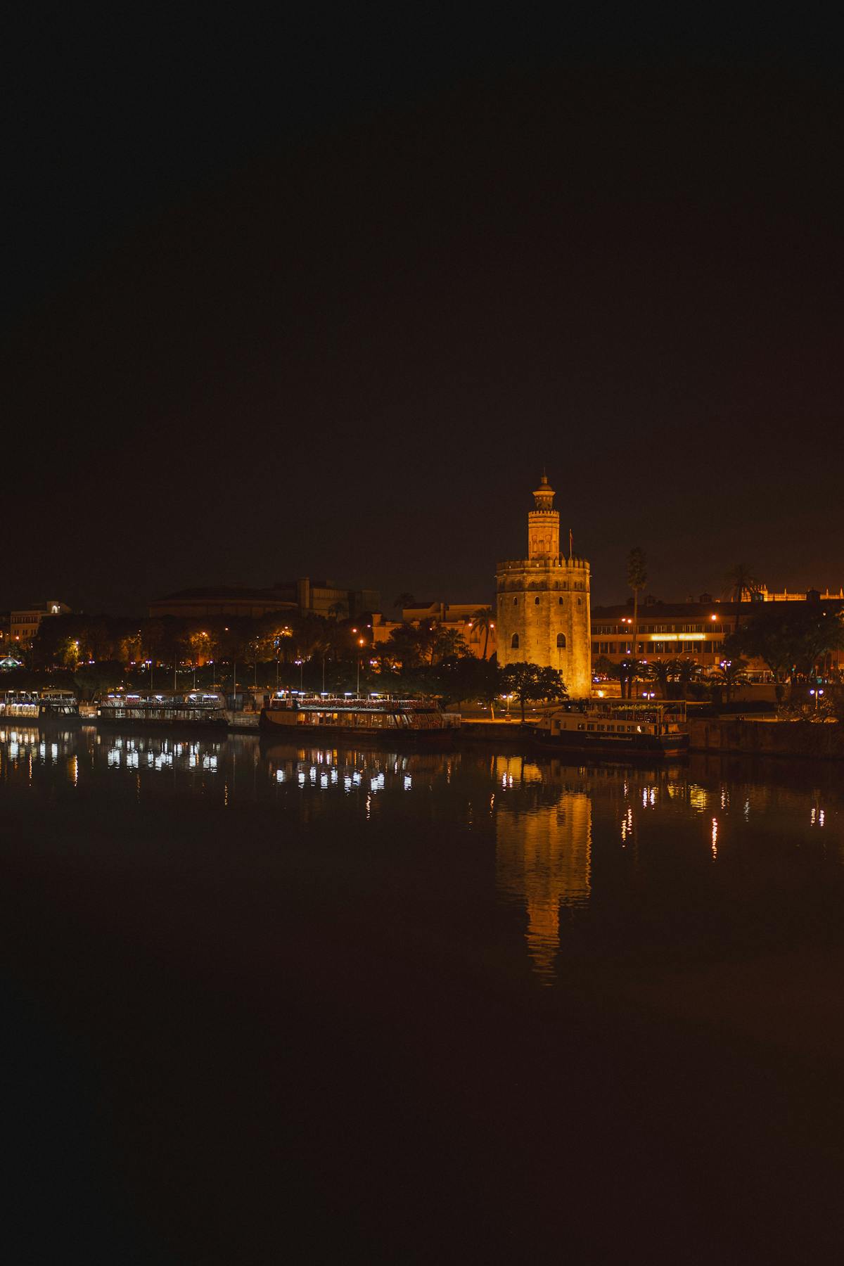 The Torre del Oro lit up at night with reflections on the Guadalquivir River in Seville