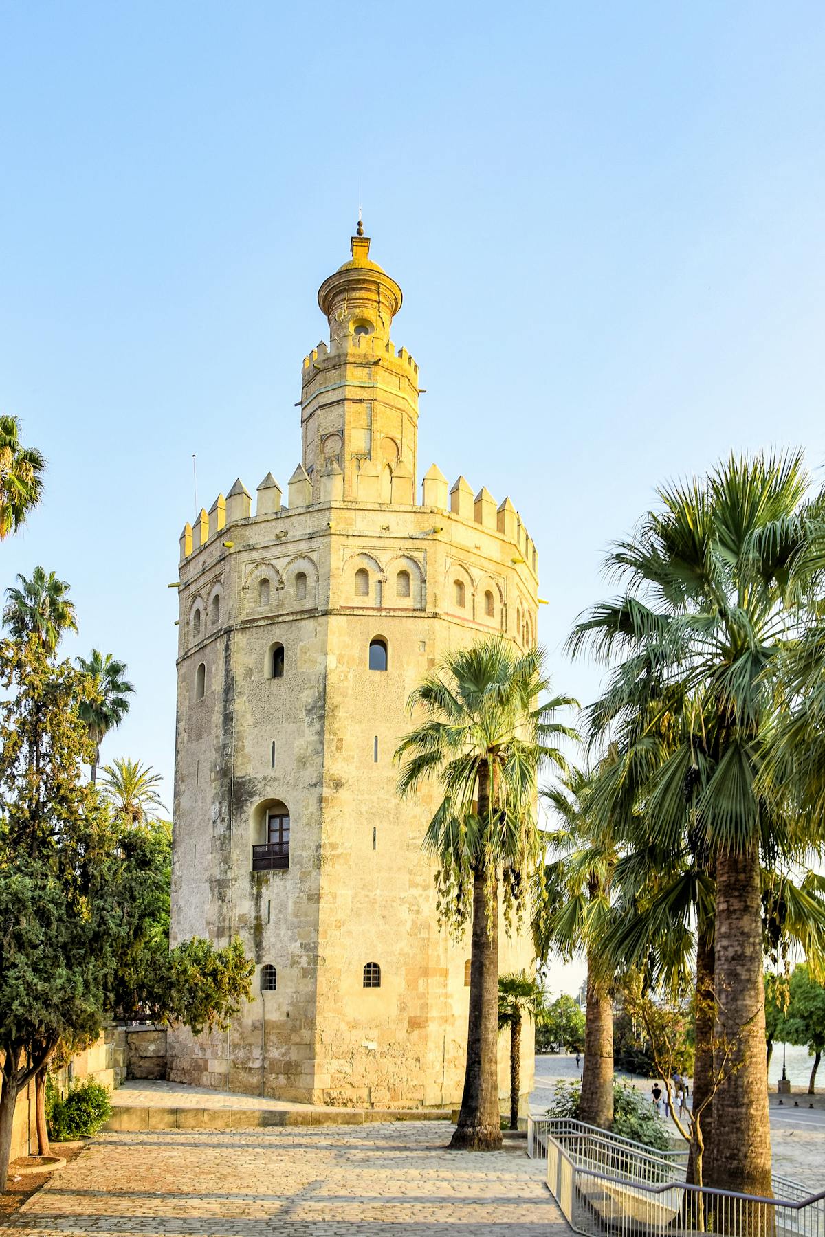 The historic Torre del Oro tower surrounded by palm trees in Seville on a sunny day