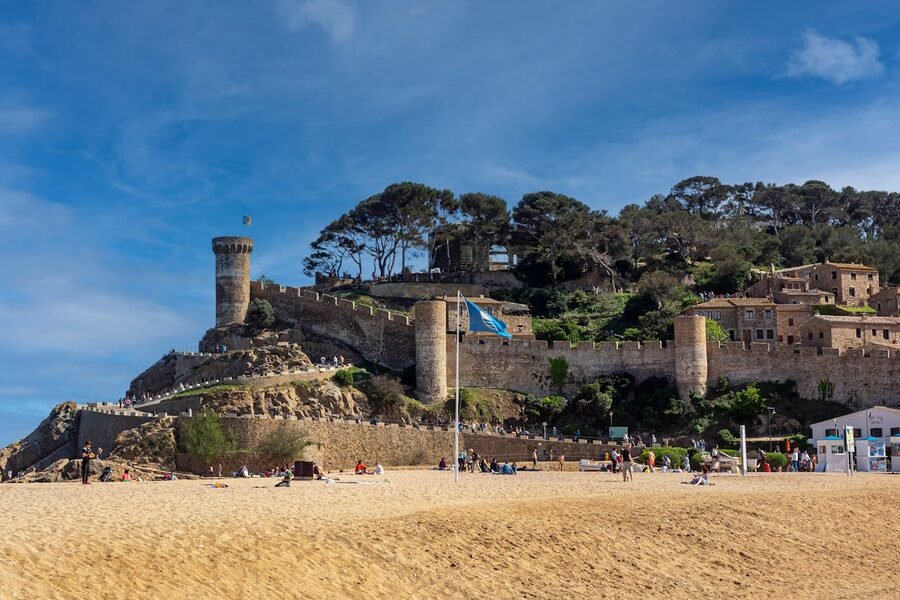 The medieval castle of Tossa de Mar overlooking the town sandy beach on a sunny day