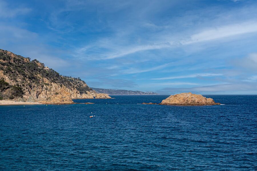 Rocky coast at Tossa de Mar with clear blue Mediterranean water stretching to the horizon