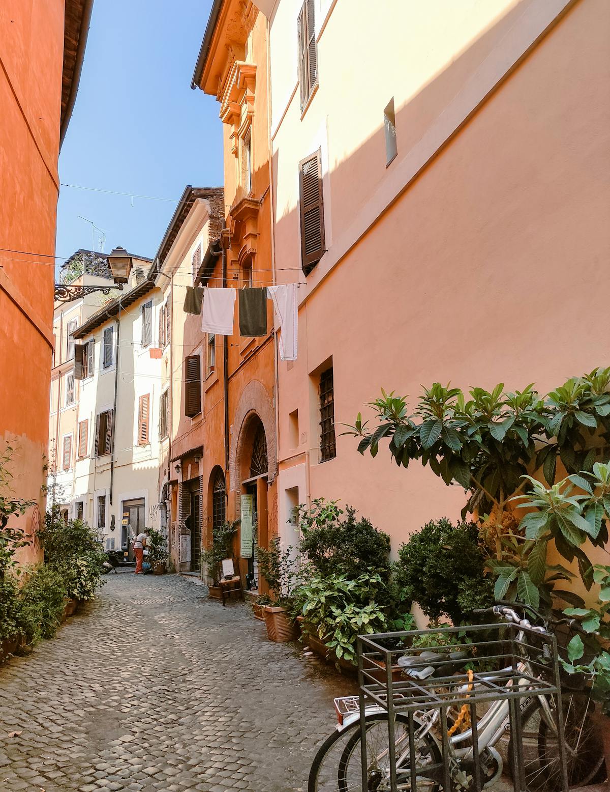 Sunlit cobblestone alley in the Trastevere neighborhood of Rome with colorful buildings