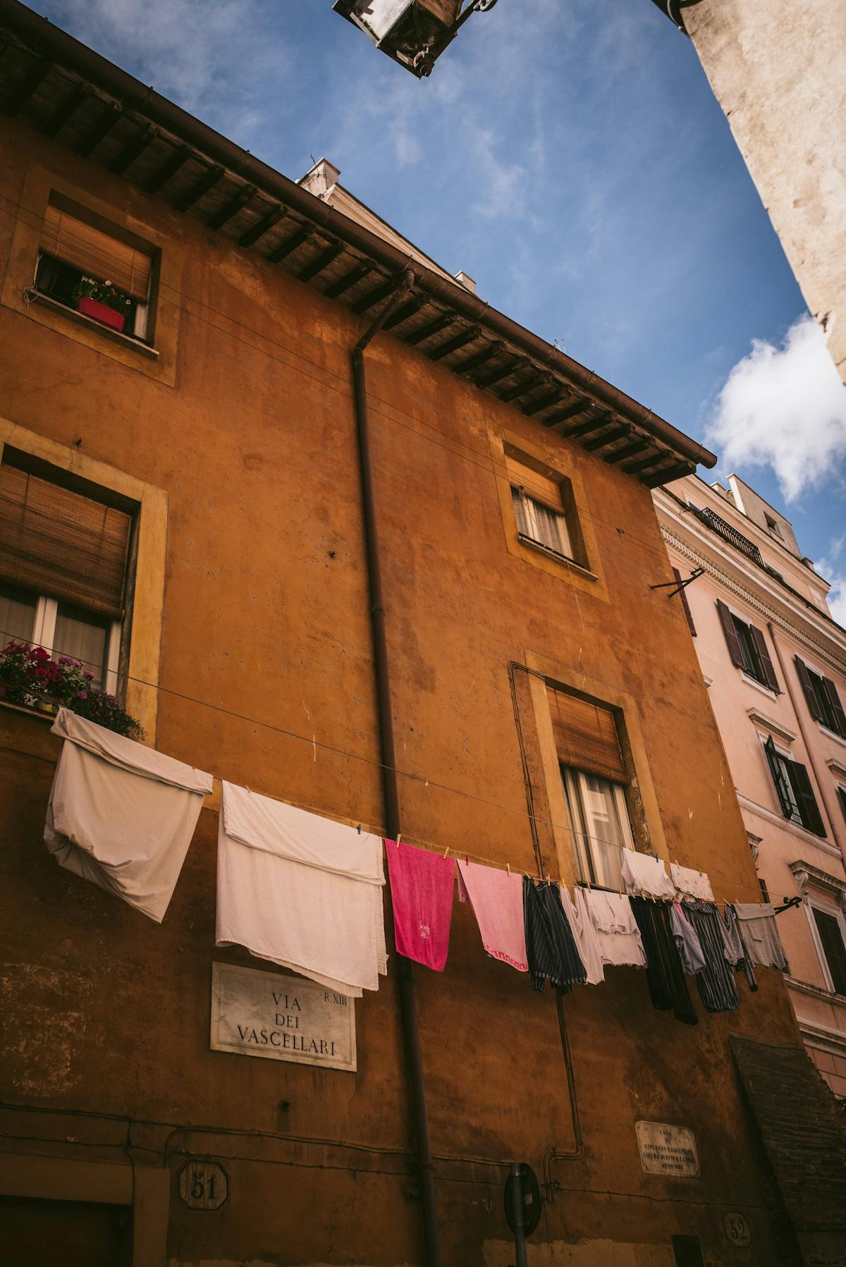 Laundry hanging between colorful buildings in a Trastevere alley