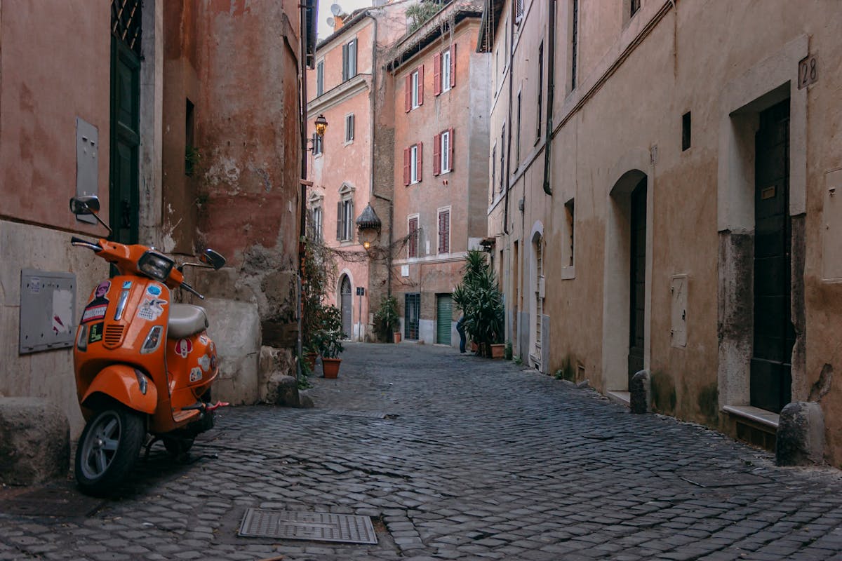 Orange Vespa scooter parked on a cobblestone street in Trastevere