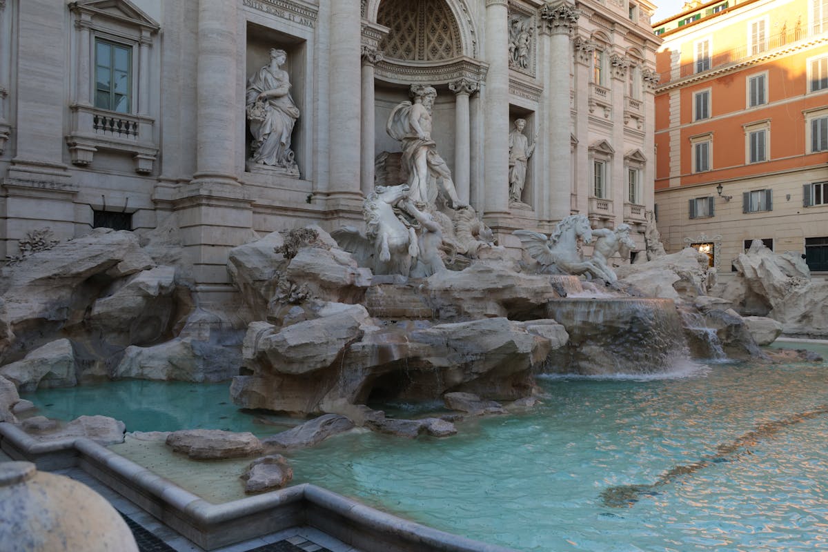 Trevi Fountain in Rome during the day with travelers gathered around the turquoise water