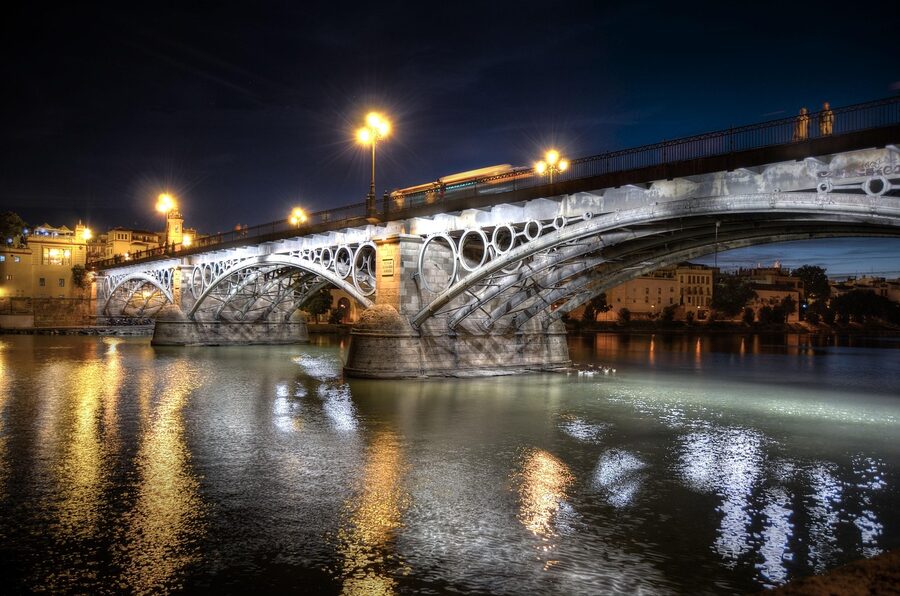 The Triana Bridge in Seville illuminated at night over the Guadalquivir River