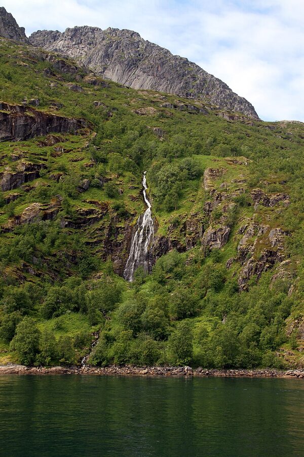 Waterfall cascading down cliff face inside Trollfjord, Lofoten