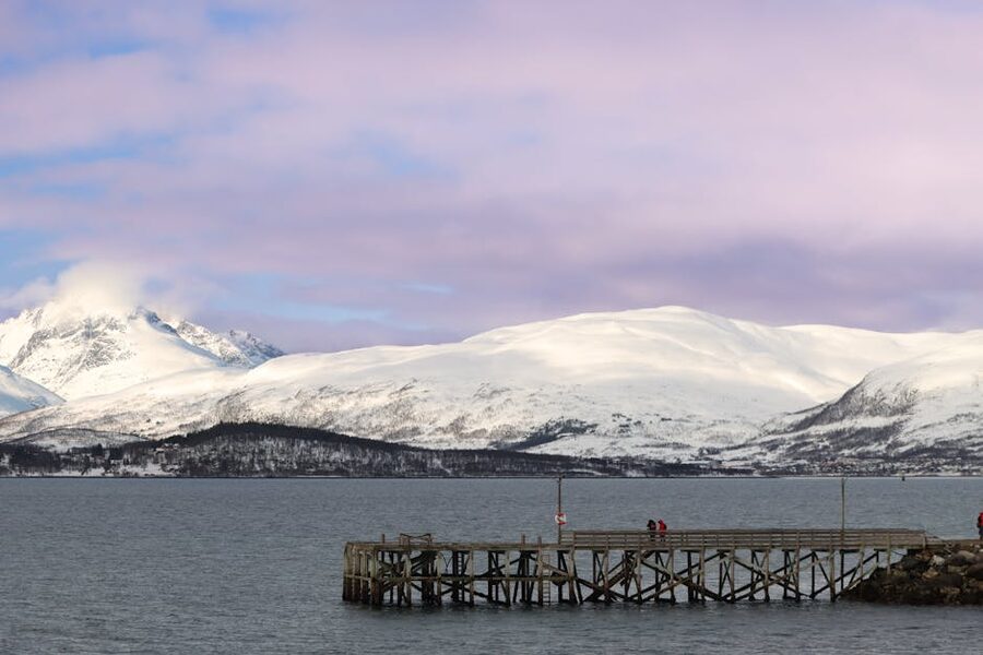 Tromso fjord with wooden pier and snowy mountains