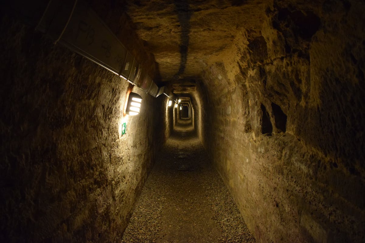 Stone-walled underground passage in the Paris Catacombs with dim lighting