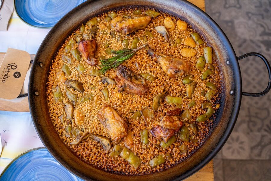 Authentic Valencian paella in a pan with chicken vegetables and rosemary