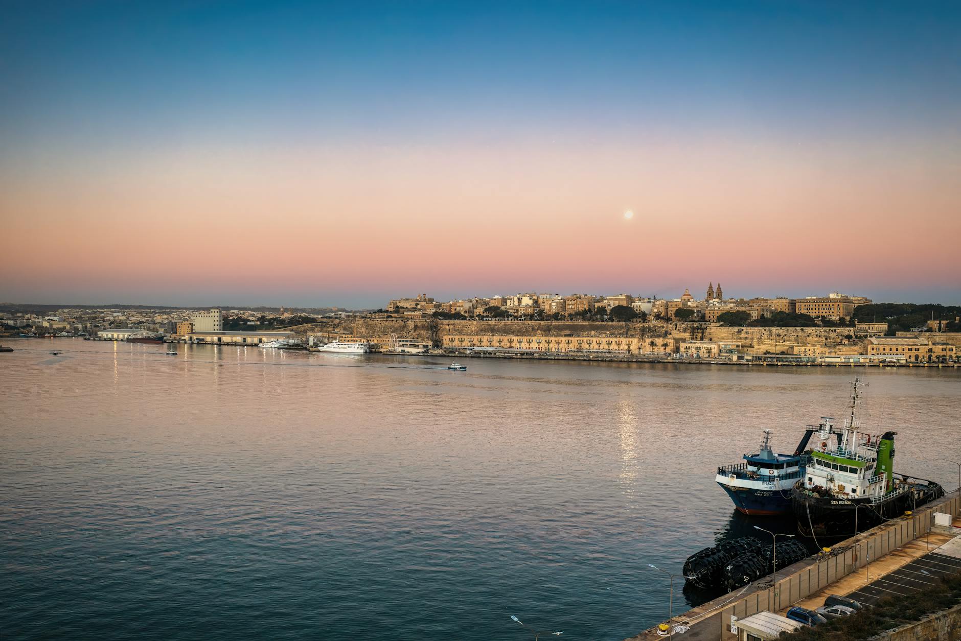 Sunset light on Valletta historic harbour with docked ship