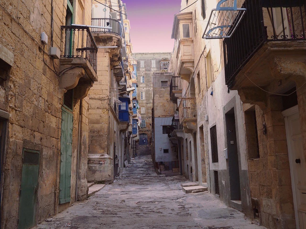 Medieval stone alley in Valletta with traditional architecture and balconies