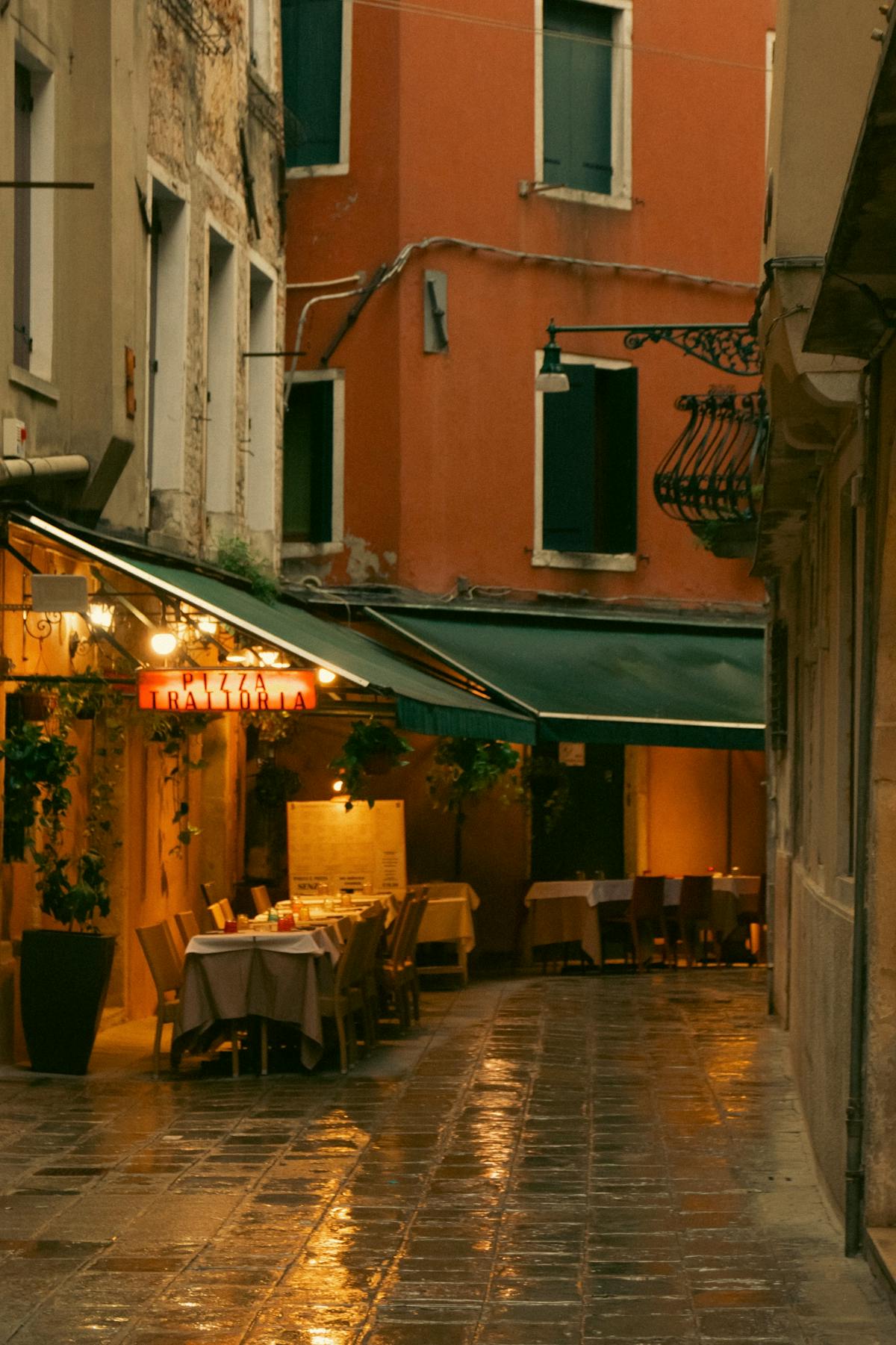A cozy Venice alley with cafe lights glowing in the rain