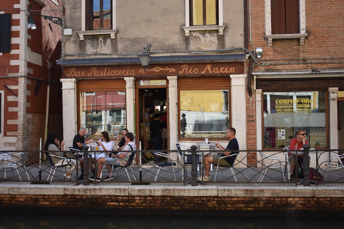 People dining at an outdoor cafe beside a Venice canal