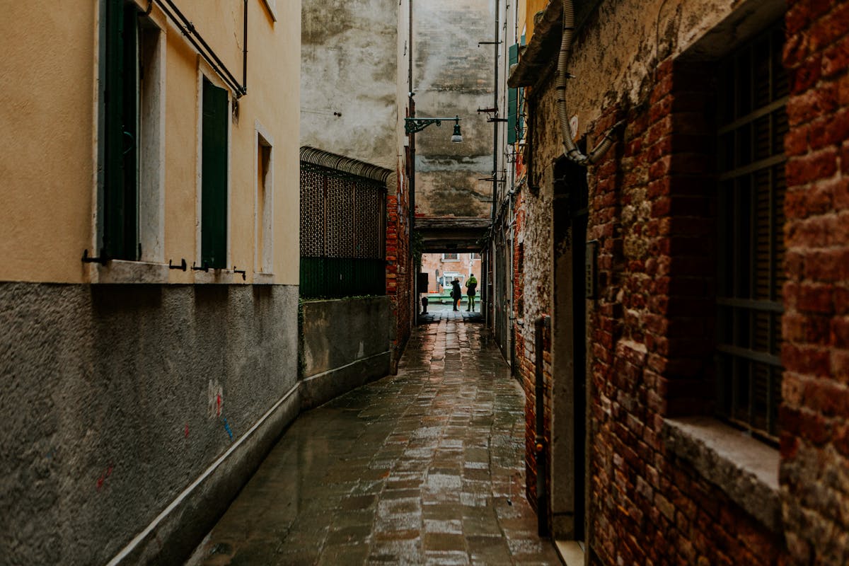 Rustic Venice alleyway with wet cobblestones and historic architecture