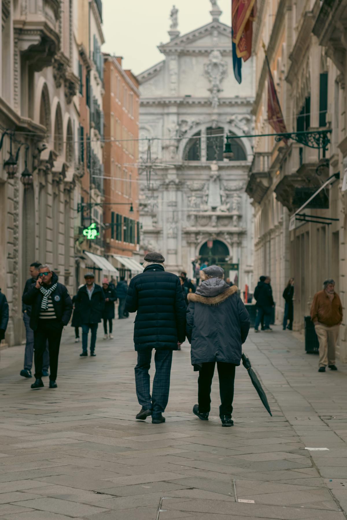Couple walking through a Venice street lined with historic architecture