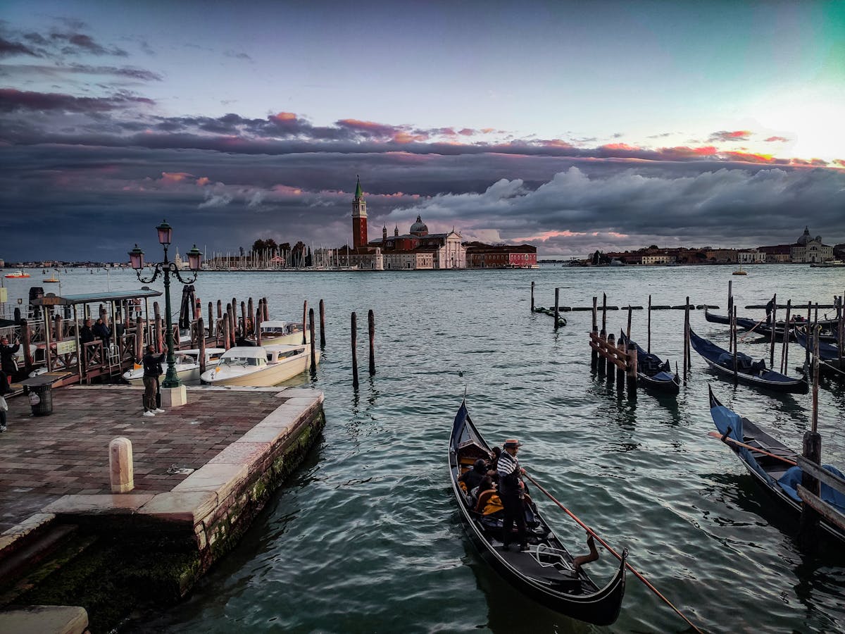 Scenic view of a Venice canal at sunset with gondolas and historic buildings